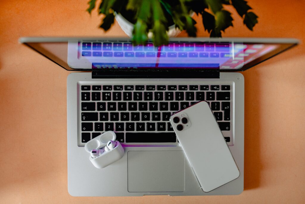 Colorful flat lay workspace with wireless headphones, iphone, macbook and a plant