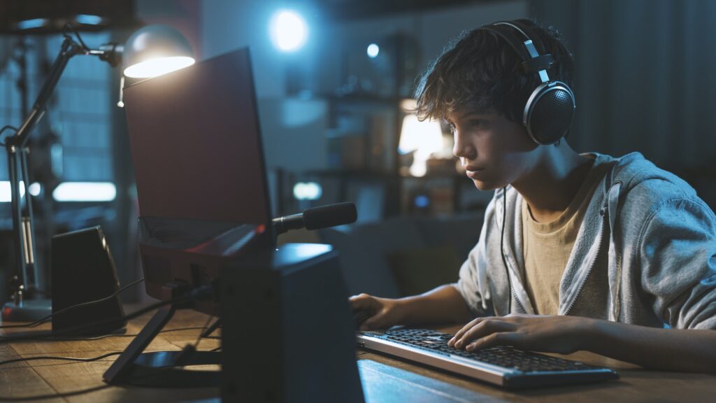 Teenager wearing headphones and playing online video games